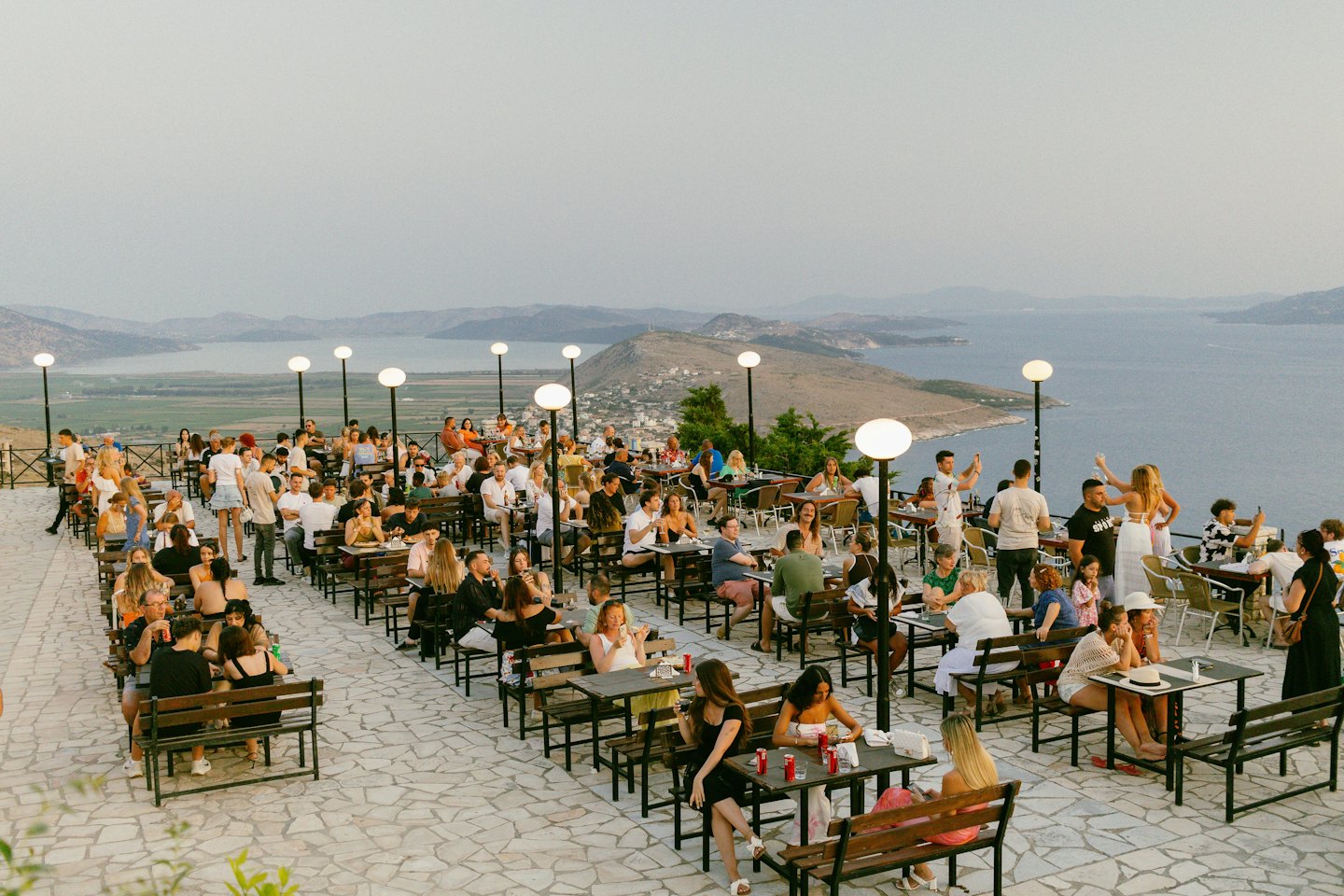 People dining on an outdoor terrace overlooking the water.