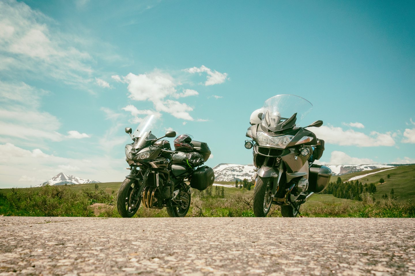 Two touring motorcycles parked beside a mountain road.