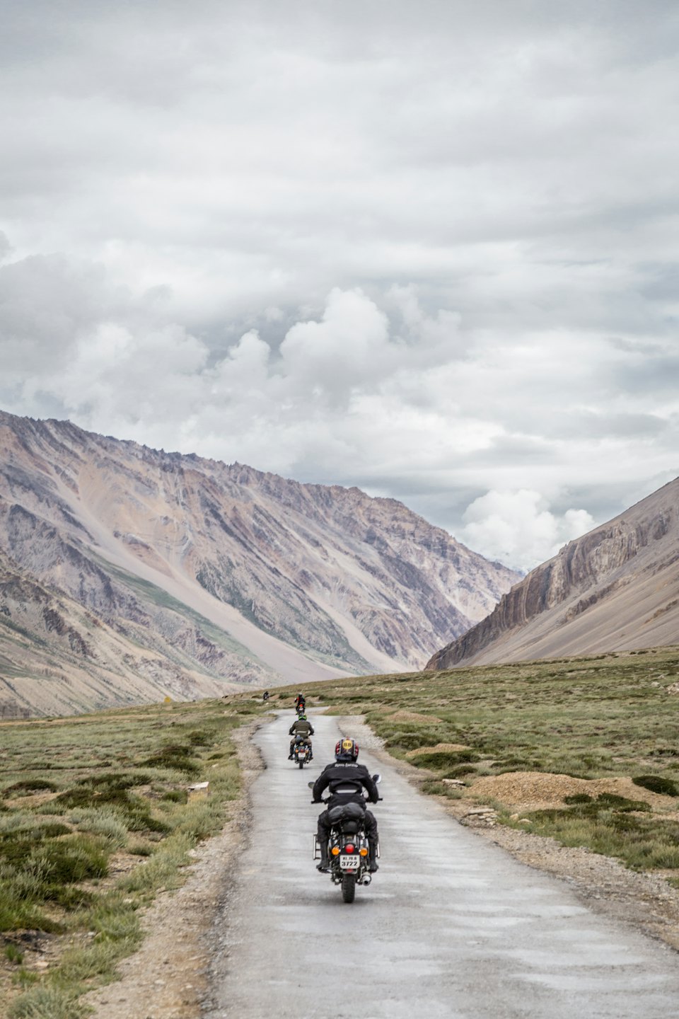 Motorcyclists ride along a winding mountain road.