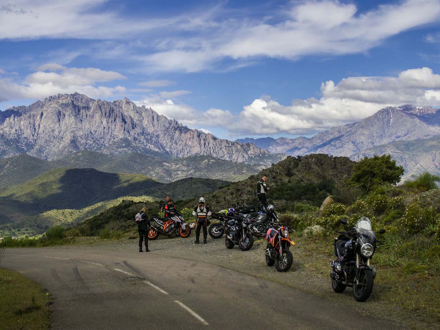 Motorcyclists take a break on a scenic mountain road.