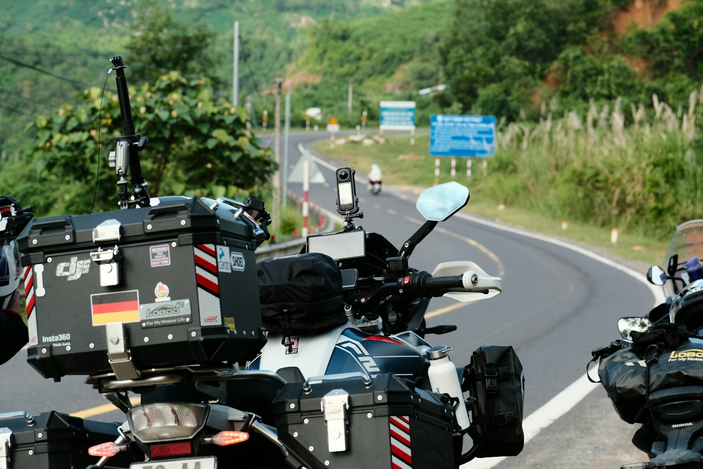 Two touring motorcycles parked along a winding mountain road.